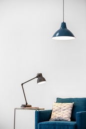 Modern lamps with blue armchair on light background