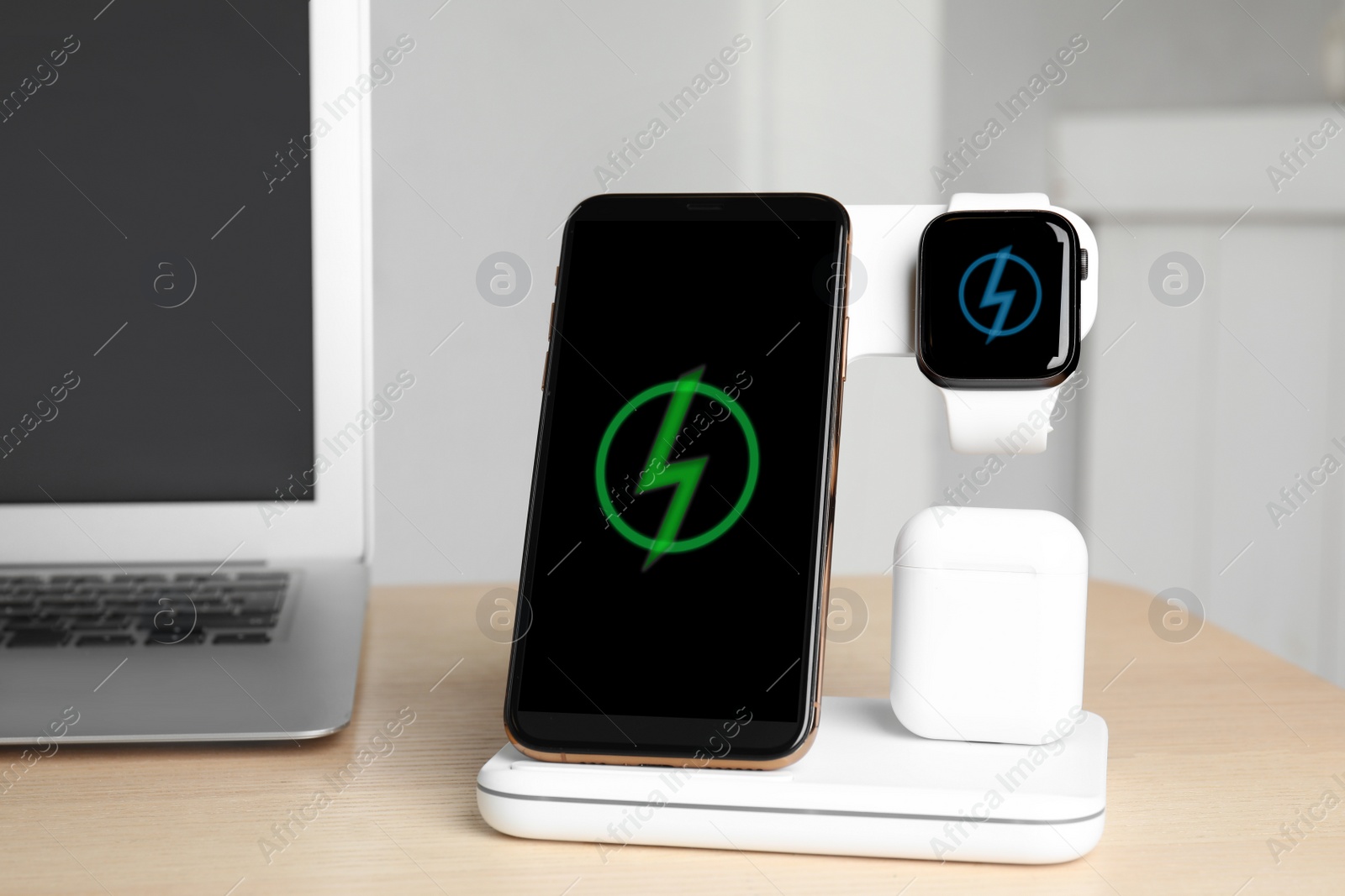 Photo of Set of gadgets charging with wireless pad on wooden table indoors