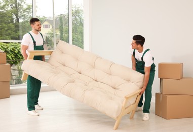 Professional movers carrying sofa in new house