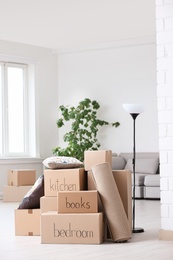 Photo of Pile of moving boxes and household stuff in living room