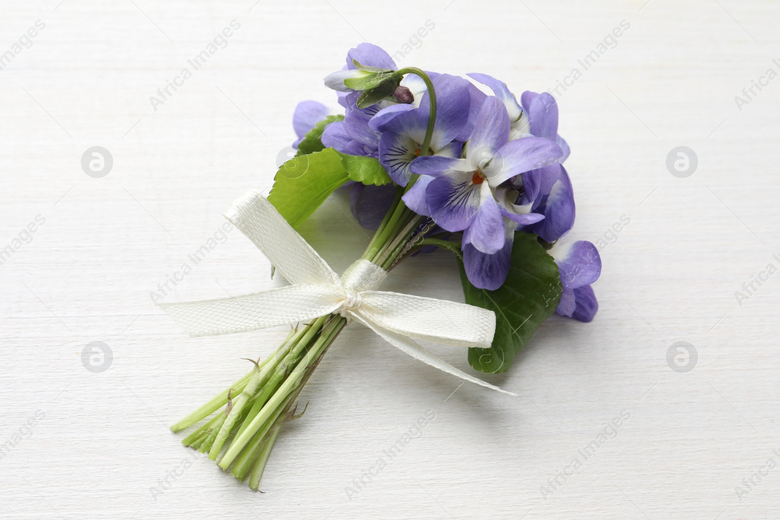 Photo of Beautiful wild violets on white wooden table, top view. Spring flowers