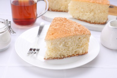 Piece of tasty sponge cake on white tiled table