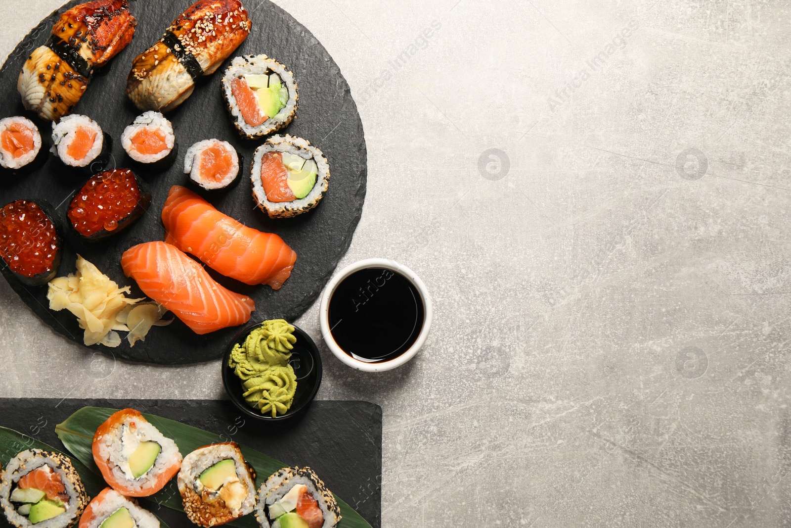 Photo of Different tasty sushi rolls on light grey table, flat lay. Space for text