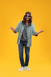 Photo of Stylish hippie man in sunglasses on orange background