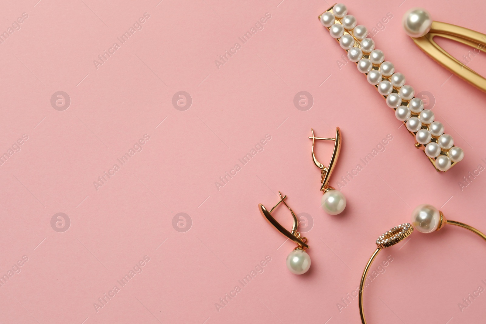 Photo of Elegant hair clips, bracelet and earrings with pearls on pink background, flat lay. Space for text