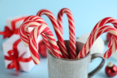 Photo of Christmas candy canes on light blue background, closeup