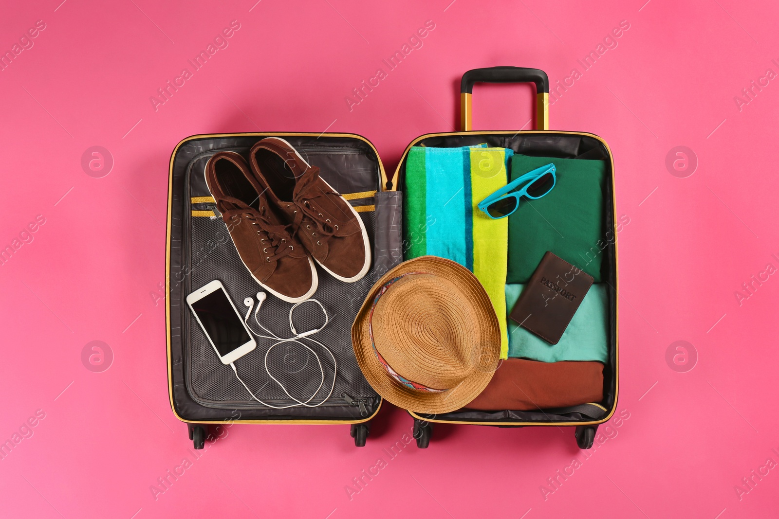 Photo of Open suitcase with traveler's belongings on color background, top view