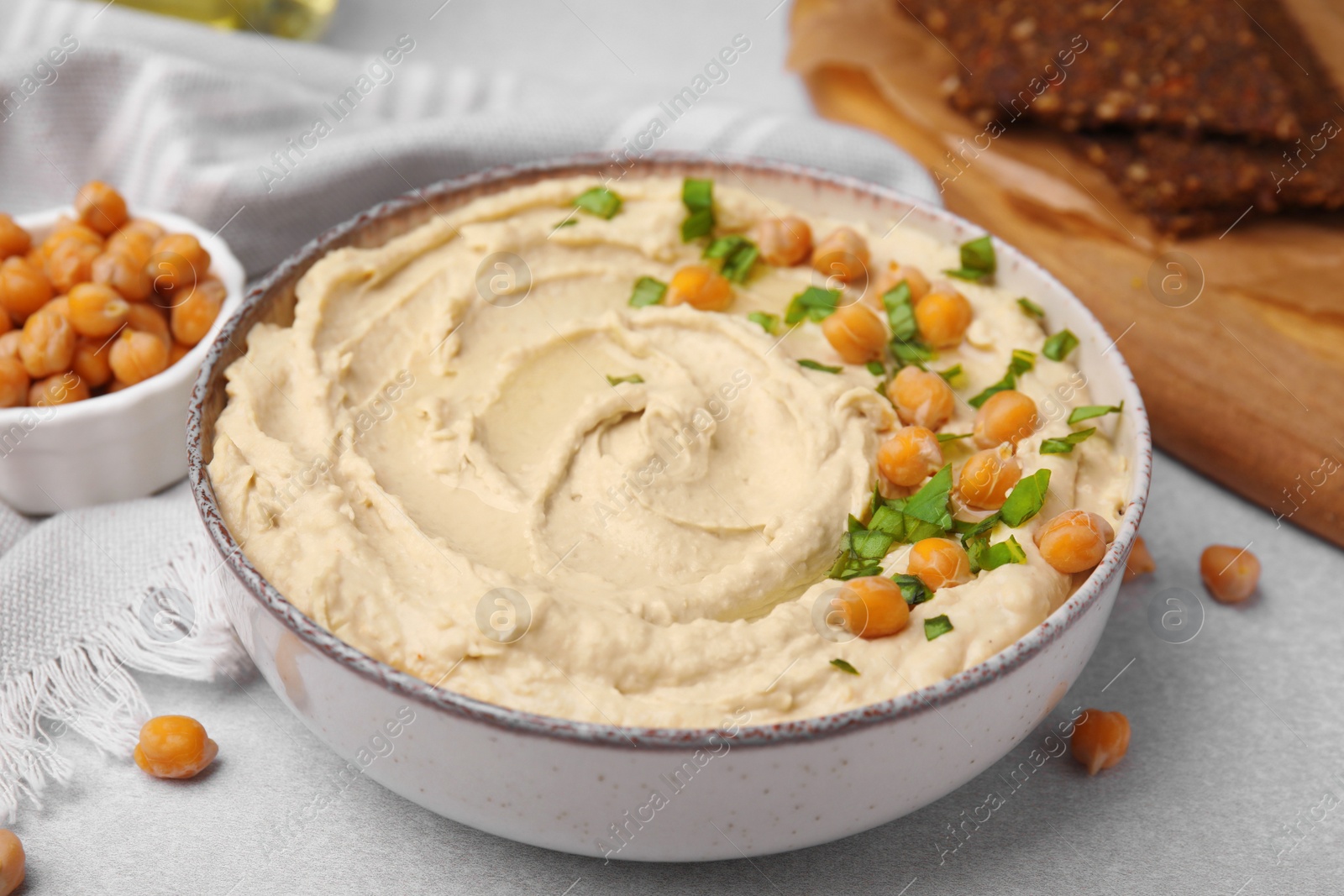 Photo of Delicious hummus with chickpeas served on light grey table
