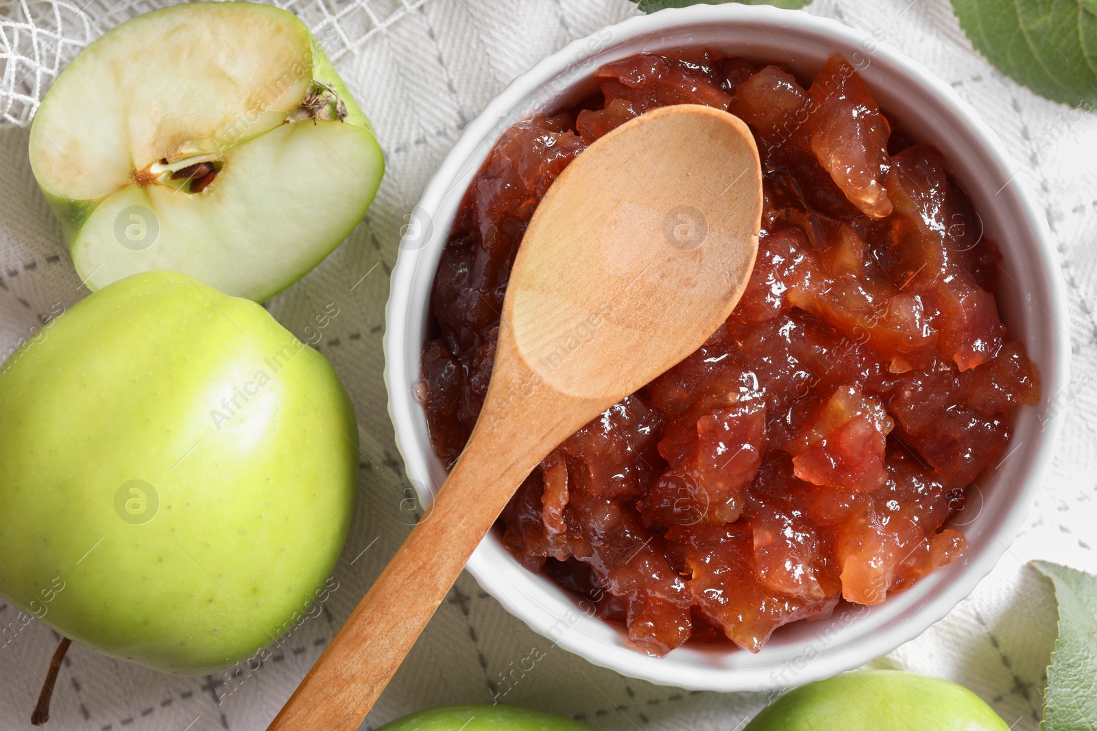 Photo of Bowl of delicious apple jam and fresh fruits on white tablecloth, flat lay