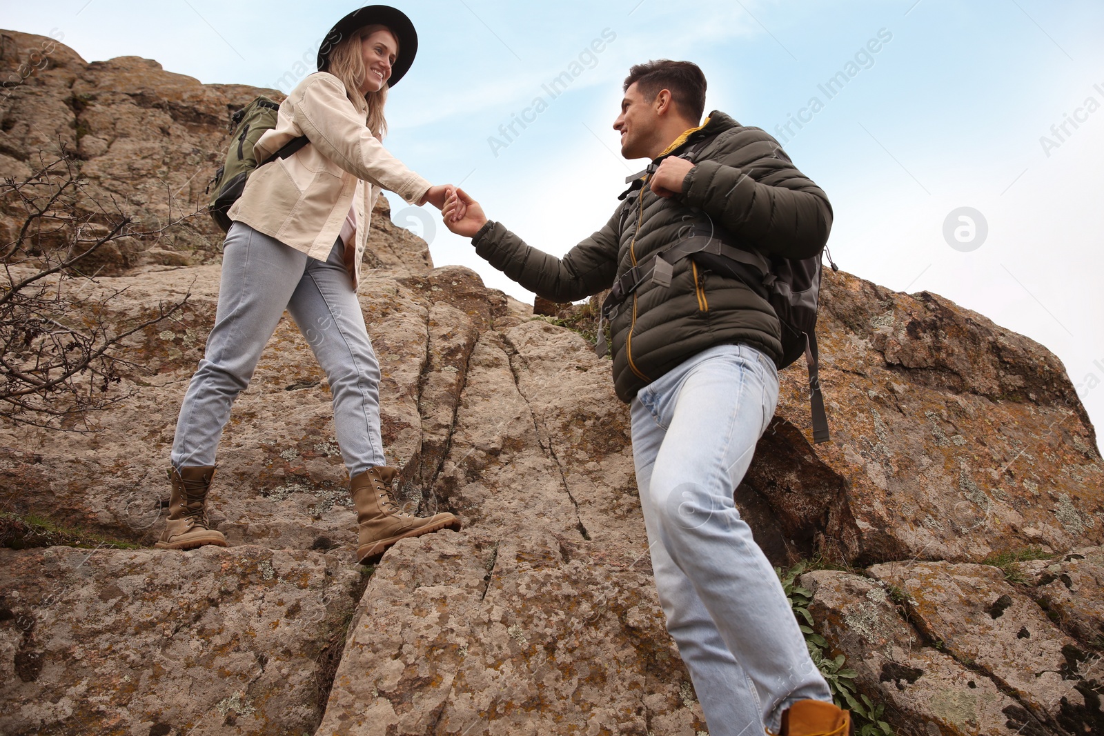 Photo of Couple of hikers with backpacks climbing down mountain