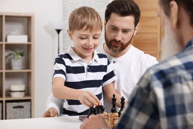 Family playing chess together at table in room