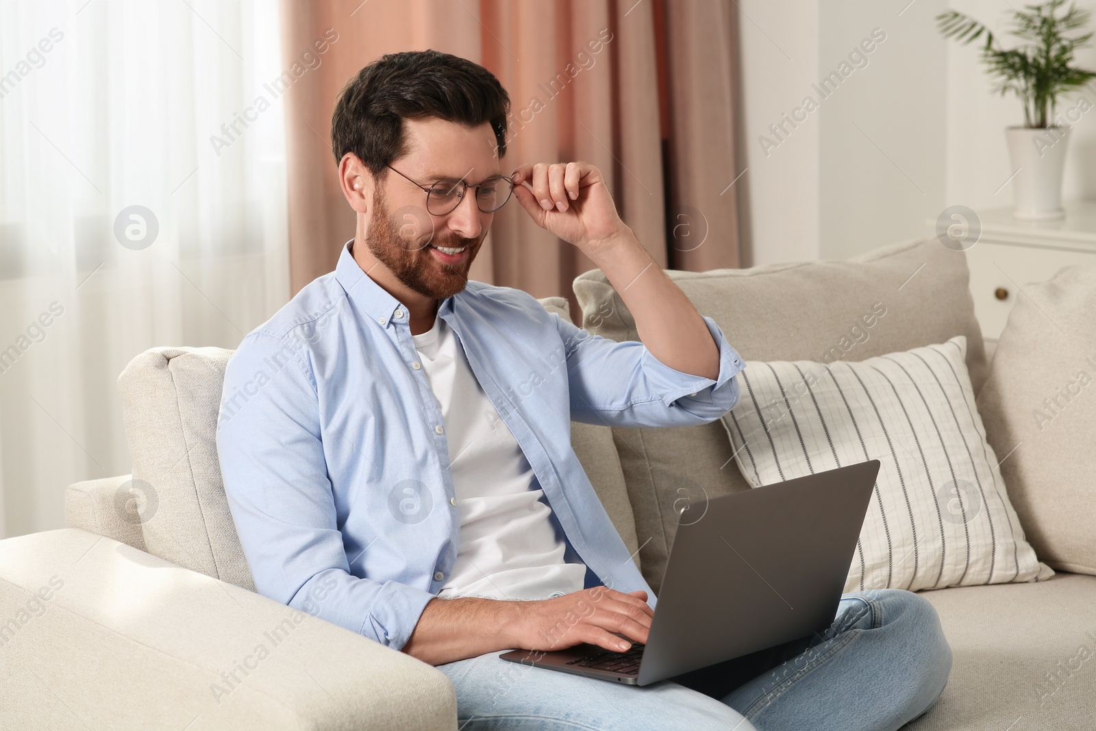 Photo of Man using laptop on sofa at home