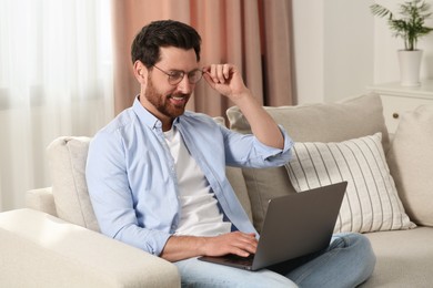 Man using laptop on sofa at home