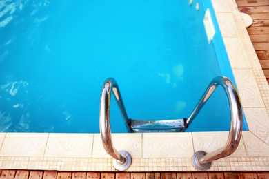 Modern swimming pool with step ladder at resort