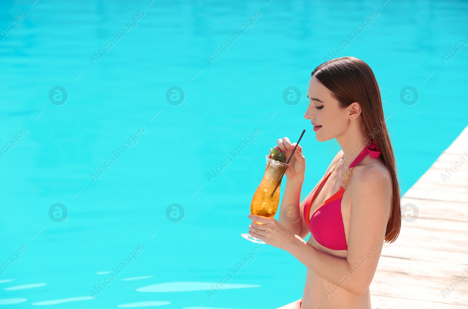 Photo of Beautiful young woman with cocktail near swimming pool