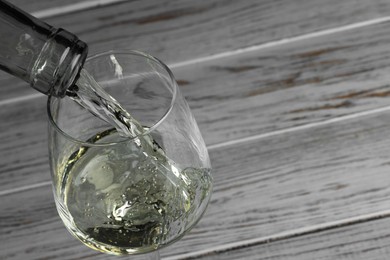 Pouring tasty aromatic wine in glass at wooden table, closeup. Space for text