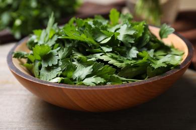Photo of Fresh green parsley in bowl on wooden table