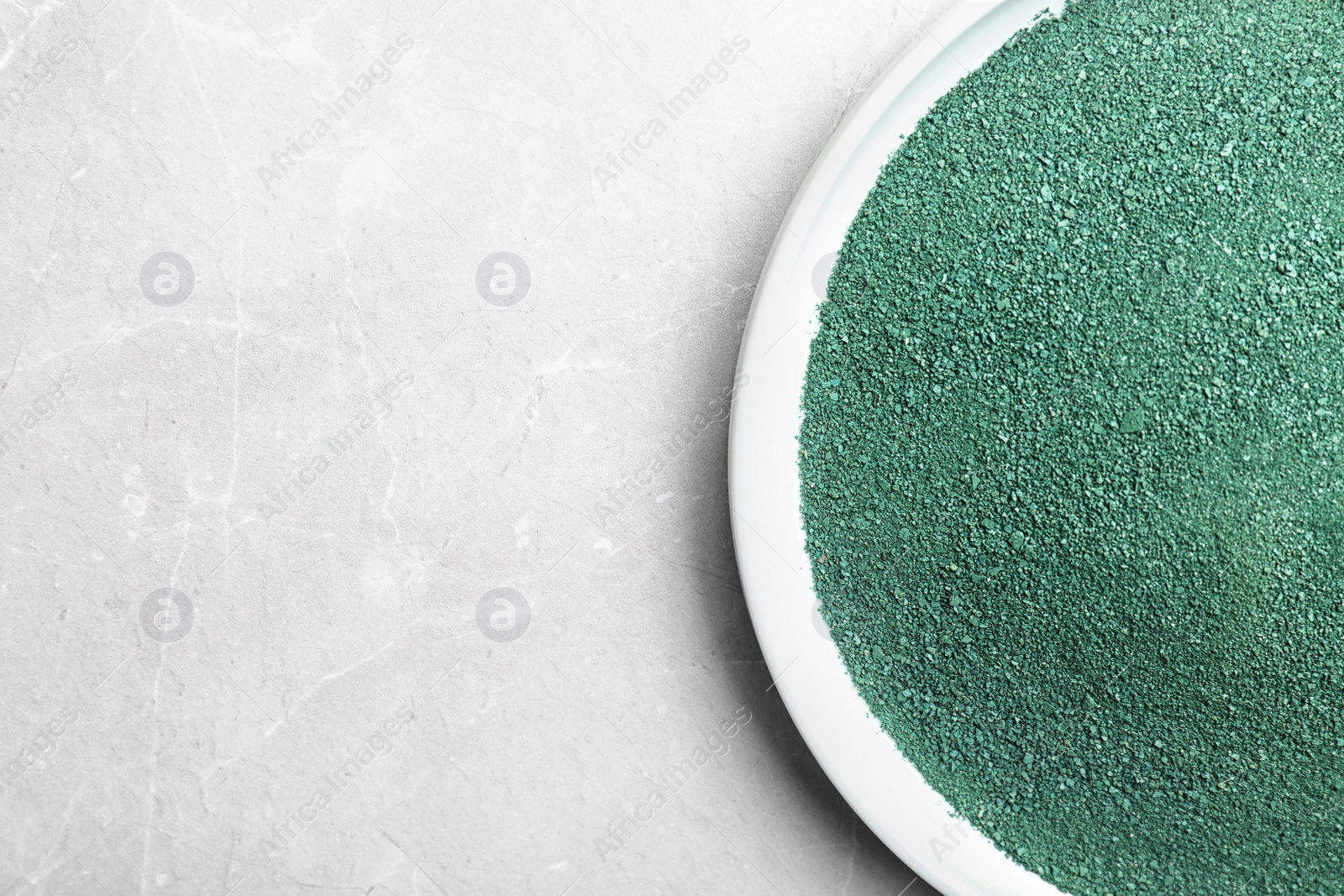 Photo of Plate of spirulina powder on light background, top view with space for text