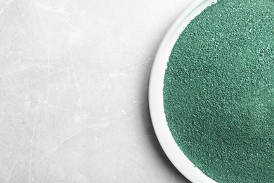 Photo of Plate of spirulina powder on light background, top view with space for text