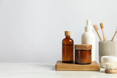 Different bath accessories and personal care products on light marble table against white wall, space for text