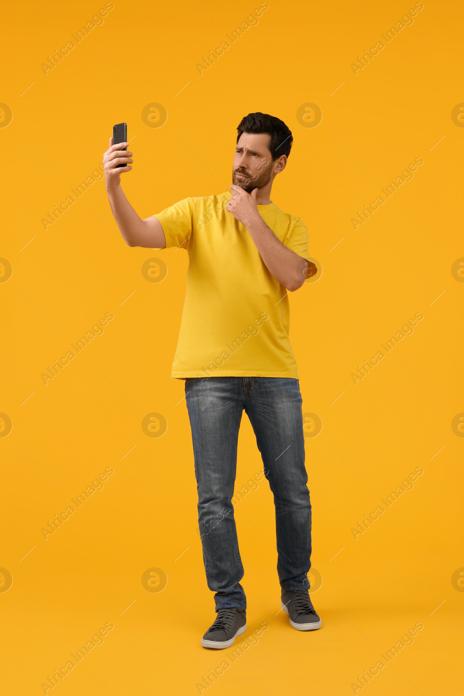 Photo of Man taking selfie with smartphone on yellow background