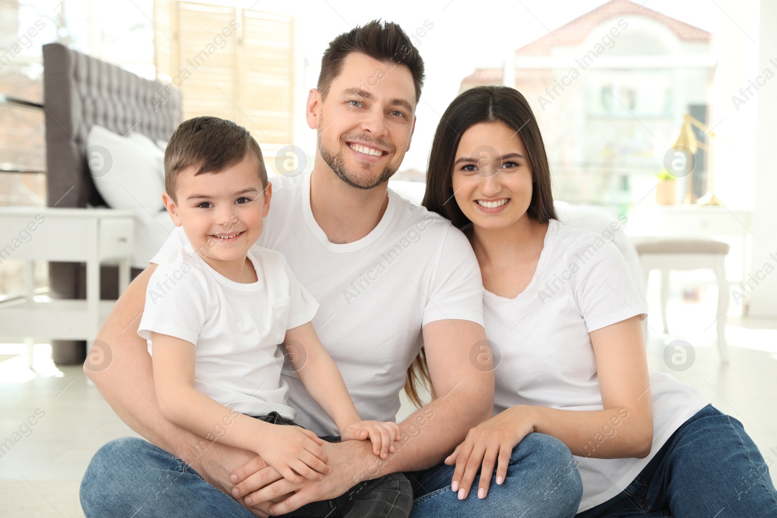 Photo of Happy parents and their son sitting together on floor at home. Family time