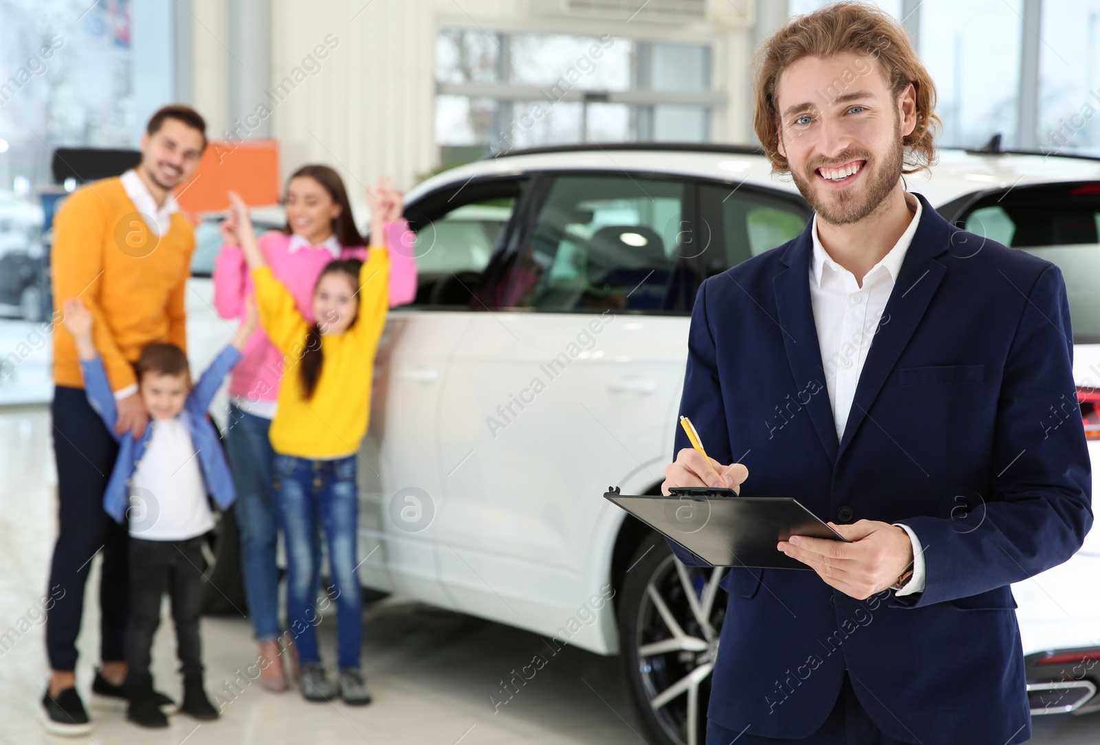 Photo of Car salesman with clipboard and blurred family near auto on background