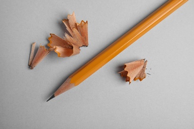 Photo of Pencil and shavings on grey background, top view