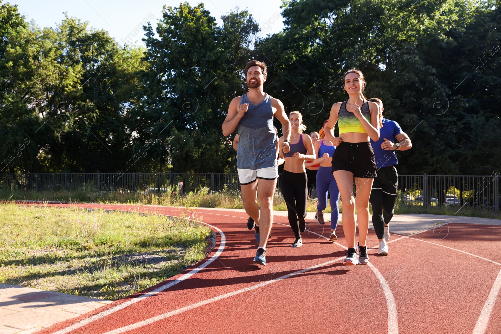 Photo of Group of people running at stadium on sunny day. Space for text