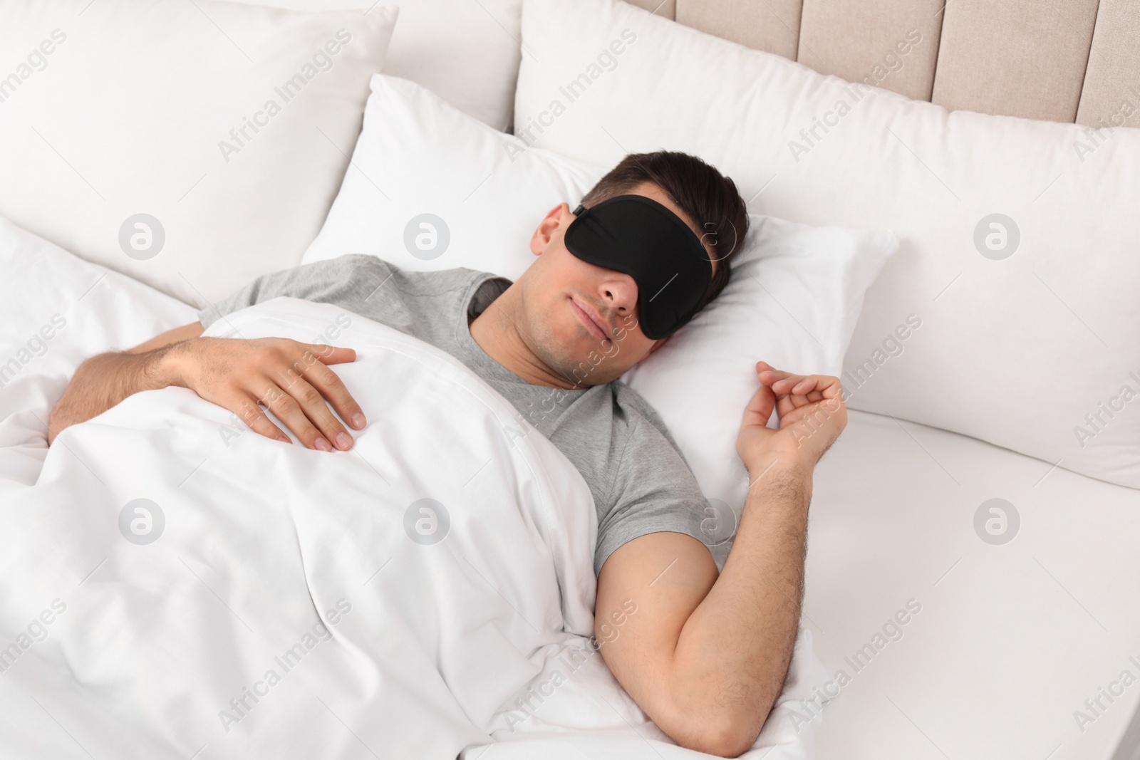 Photo of Man wearing sleeping mask in bed at home, above view