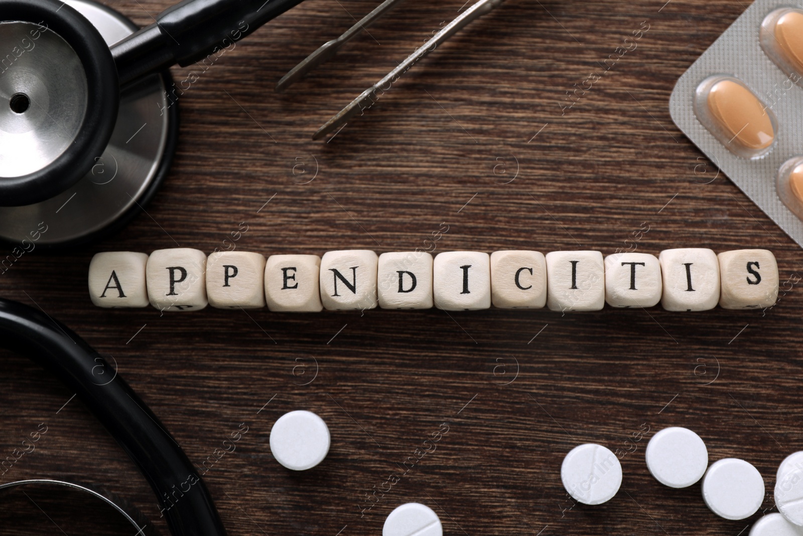 Photo of Word Appendicitis made of cubes, pills and medical supplies on wooden table, flat lay