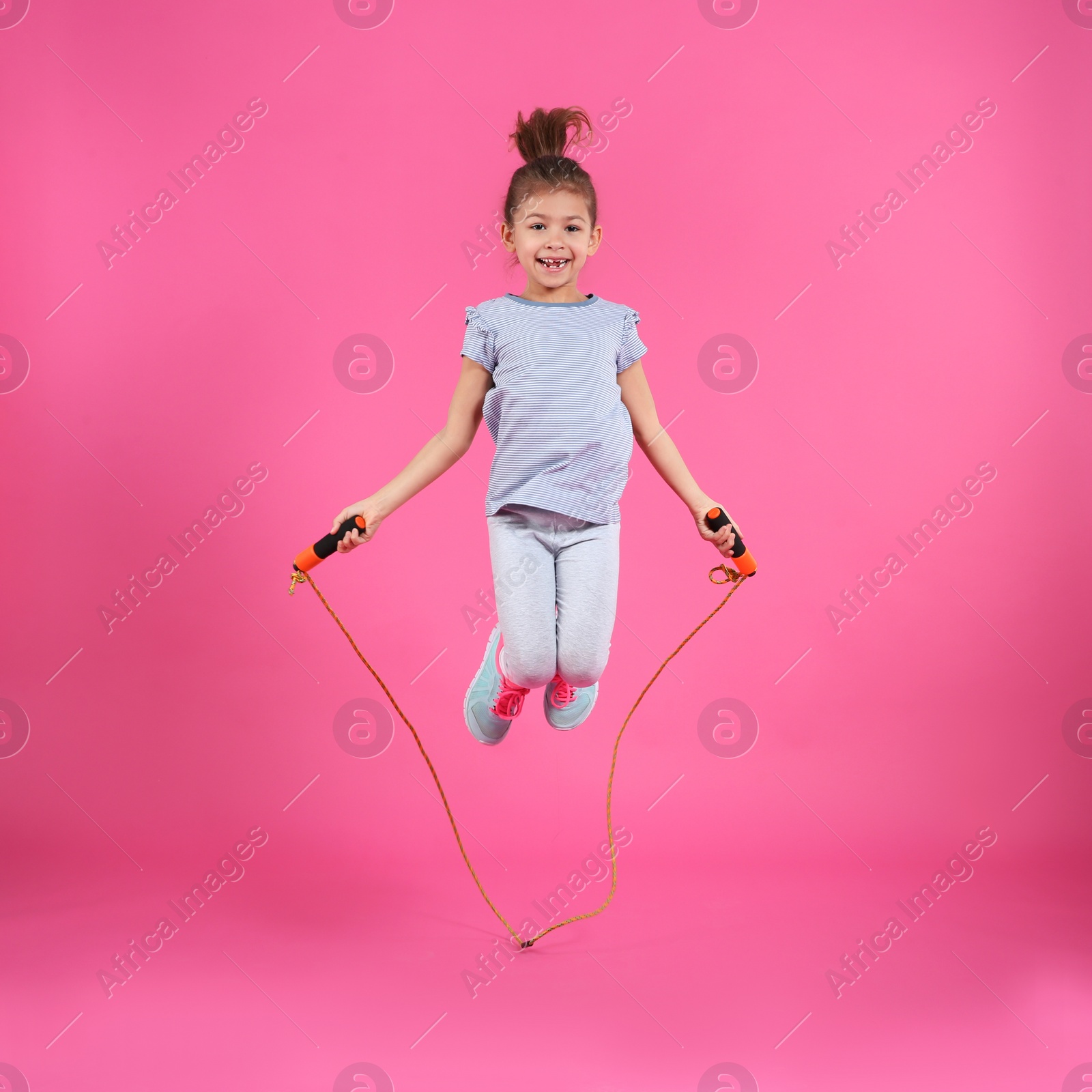 Photo of Full length portrait of girl jumping rope on color background