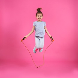 Full length portrait of girl jumping rope on color background