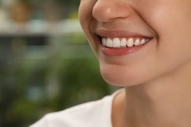 Woman with healthy teeth on blurred background, closeup. Space for text