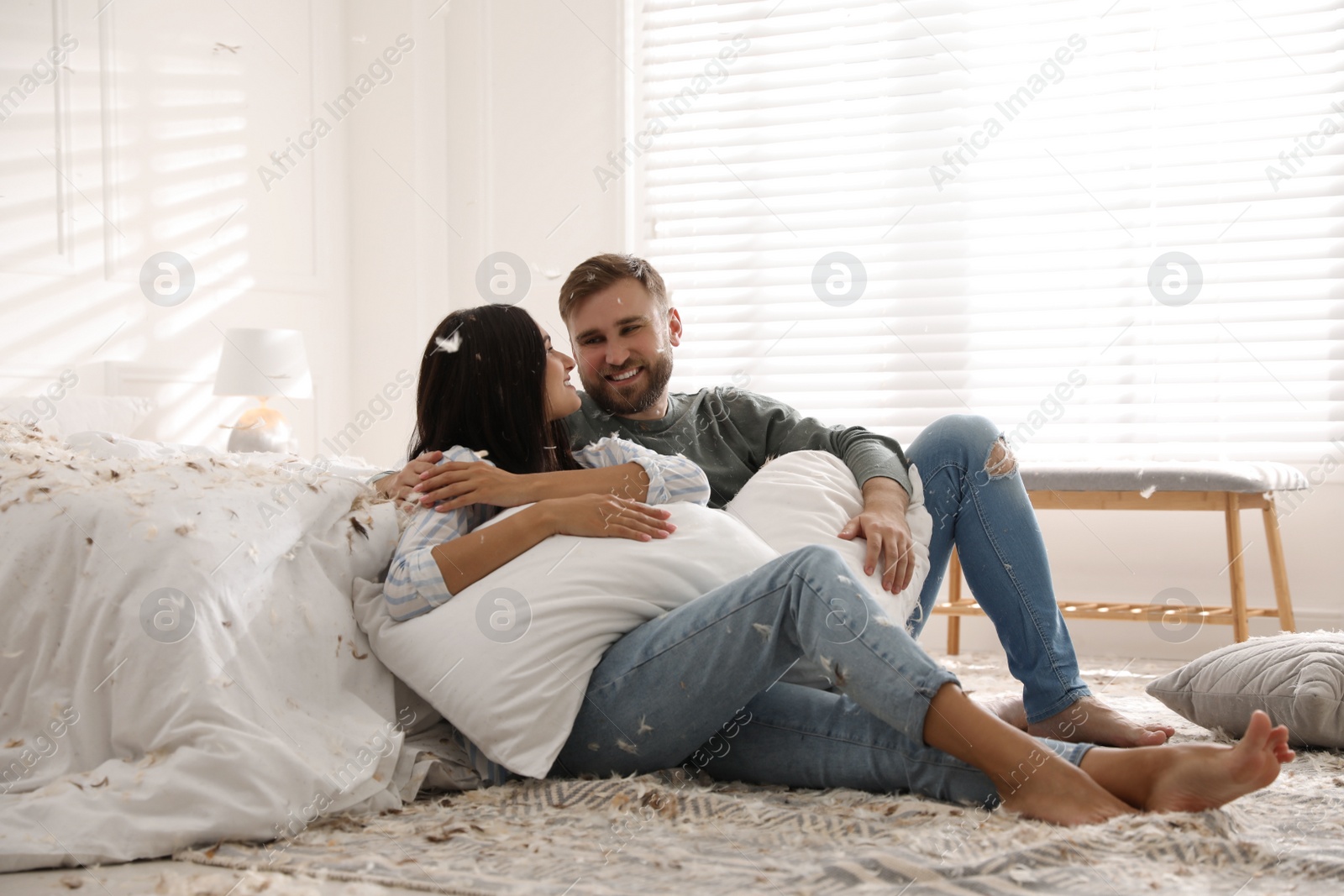 Photo of Happy young couple resting after fun pillow fight in bedroom