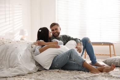 Happy young couple resting after fun pillow fight in bedroom