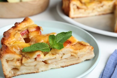 Photo of Slice of traditional apple pie with mint on plate, closeup