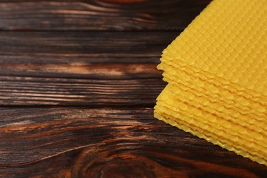 Natural beeswax sheets on wooden table, closeup. Space for text