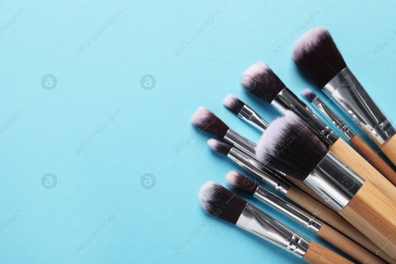 Photo of Different makeup brushes on light blue background, flat lay. Space for text