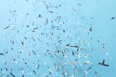 Photo of Shiny silver confetti falling down on light blue background