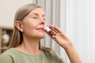 Medical drops. Woman using nasal spray indoors