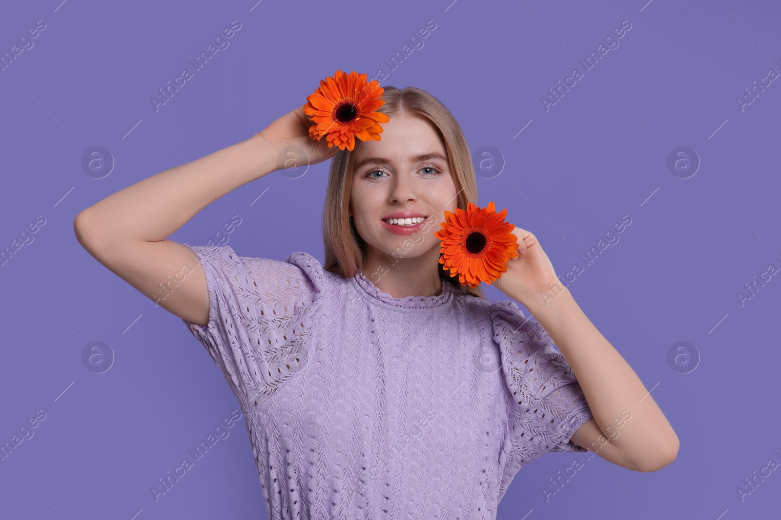 Photo of Beautiful woman with spring flowers in hands on purple background