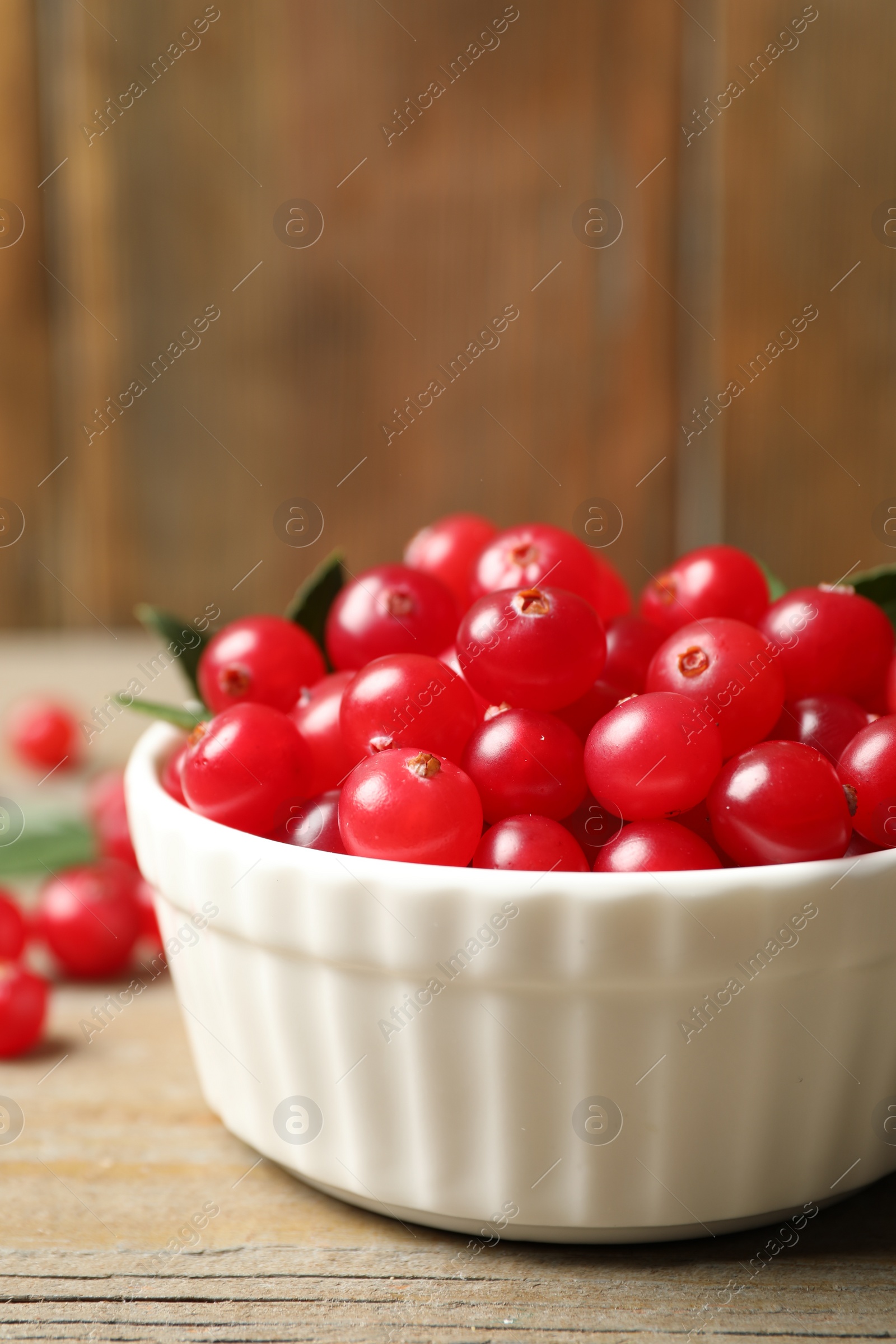 Photo of Tasty ripe cranberries on wooden table, closeup