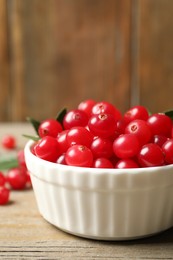 Photo of Tasty ripe cranberries on wooden table, closeup