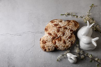 Photo of Delicious Italian Easter dove cake (Colomba di Pasqua), flowers and bunny figures on grey table, flat lay. Space for text