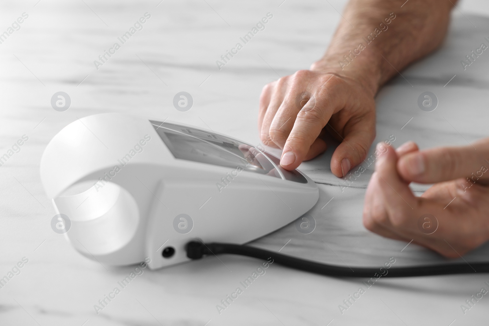 Photo of Man measuring blood pressure at white marble table, closeup