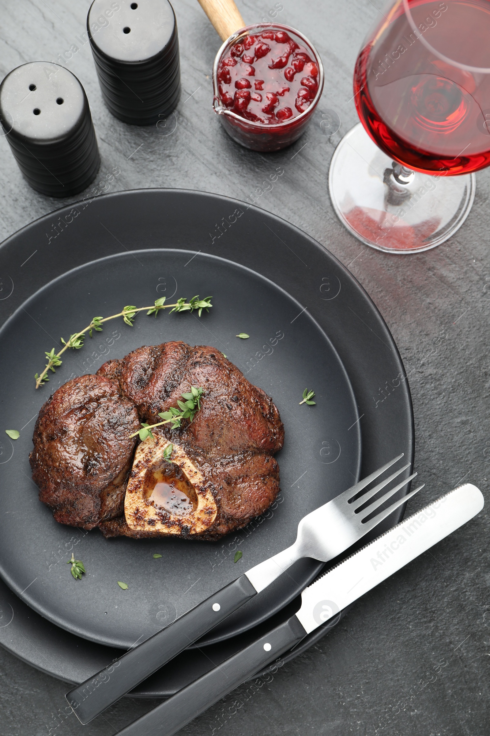 Photo of Tasty grilled beef meat served on black table, flat lay