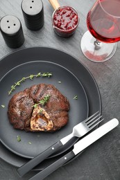 Photo of Tasty grilled beef meat served on black table, flat lay