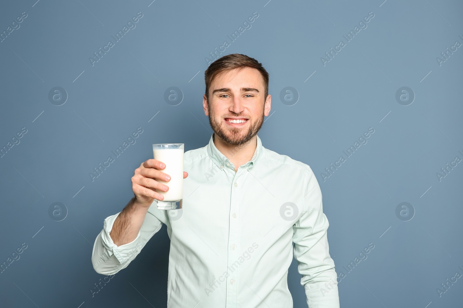 Photo of Young man with glass of tasty milk on color background