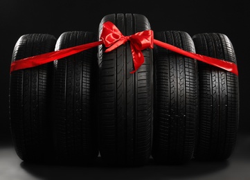 Photo of New car tires tied with ribbon on black background